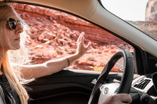 Woman Wearing Sunglasses Gesturing While Driving Car At Monument Valley Tribal Park