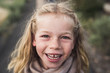 © Cavan Images - Portrait of smiling girl with blond hair standing in forest