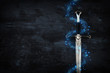 low key image of silver sword with magical lights. fantasy medieval period.