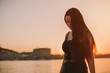 © Cavan Images - Sad woman with long hair walking by river against clear sky during sunset