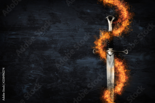 Fotografía low key image of silver sword in the flames of fire