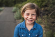 © Cavan Images - Portrait of smiling girl with blond hair standing outdoors