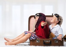 Funny Kids Sitting At Suitcase And Fooling Around On Background