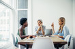© Cavan Images - Happy businesswomen discussing at conference table in creative office