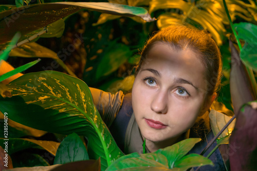 Fotografia, Obraz young female traveler in rainforest among tropical plants looking up