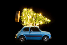Blue Retro Toy Car Delivering Christmas Or New Year Illuminated Tree On Black Background