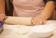 © lashkhidzetim - Female hands rolling out dough on kitchen table, close up