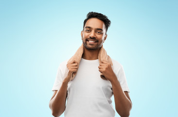 Wall Mural - grooming and people concept - smiling indian man with bath towel over blue background