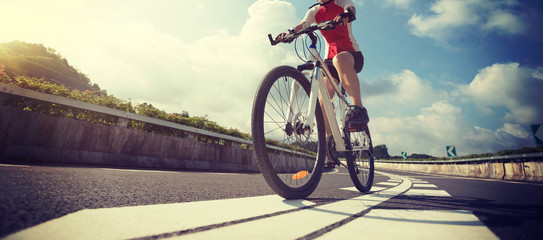 Woman cyclist riding Mountain Bike on highway