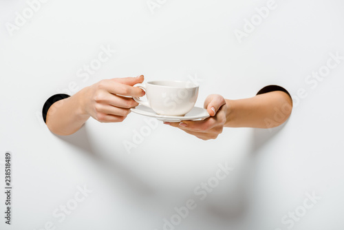 Fotografie, Obraz cropped image of woman holding cup of coffee and plate through holes on white