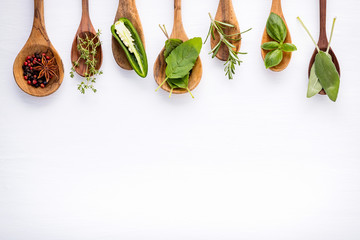 Wall Mural - Various of spices and herbs on wooden background. Flat lay spices ingredients rosemary, thyme, oregano, sage leaves and sweet basil on dark wooden.