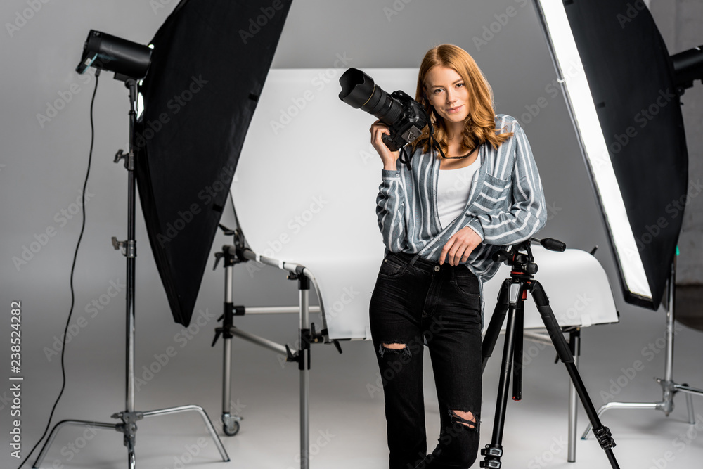 attractive young female photographer working in professional photo studio - obrazy, fototapety, plakaty 