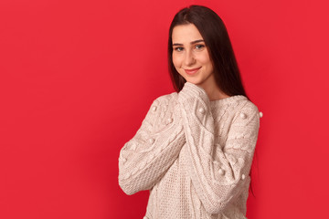 Freestyle. Young woman standing isolated on red hands together smiling cute side view