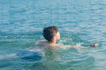 Wall Mural - Happy and smiling teen boy swimming in the sea. Travel and summer concept