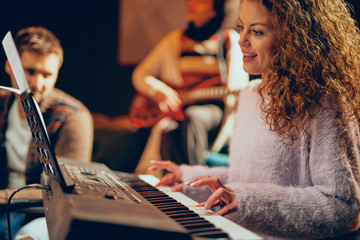 Sticker - Guitarist showing woman how to play clavier. Selective focus on woman. Home studio interior.