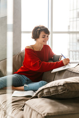 Wall Mural - Cheerful girl studying at home while laying