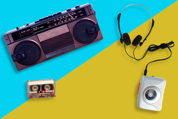 Wall Mural - Portable tape player with radio and cassette tape and Headphone on a split yellow and blue background, gadgets for The 70-80-90's