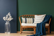 © Photographee.eu - Natural wicker settee with striped pillows and blanket next to white flower in glass vase, real photo with copy space on empty green and blue wall