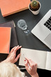 © olgapogorelova - Close up of woman's hands making notes on white spread book. CActus and glass of water. Young woman or student working and writing on paper notebook, space for text.