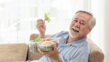 Lifestyle senior man feel happy enjoy eating diet food fresh salad on sofa