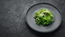 Seaweed Salad In A Black Plate. Chuka Wakame On The Old Background. Top View. Free Space For Your Text.