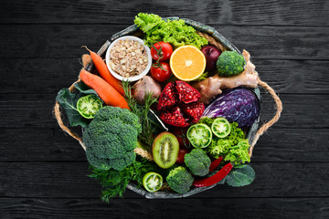 Fresh vegetables and fruits in a wooden box on a black background. Organic food. Top view. Free copy space.