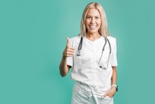 Girl Doctor With Stethoscope Around His Neck Standing On Green Background Shows Famously Raised His Finger Up