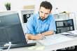 © Ivan Traimak - A young man standing in the office at a computer Desk and working with a magnetic Board.