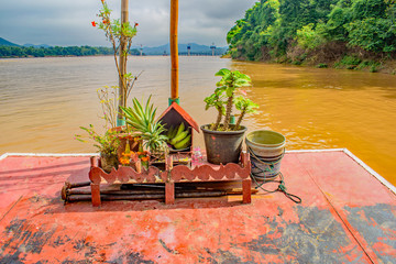 a shrine sits on the red prow of a tour boat sailing along the mekong river
