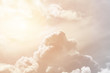 Soft cumulus fluffy clouds illuminated by the sun against a orange sky (background, toned)
