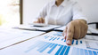 © Ngampol - Business woman accountant working and calculating financial data on graph documents, doing finance in workstation