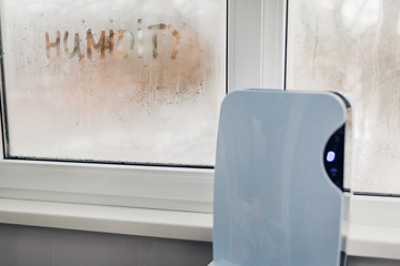 Wall Mural - Dehumidifier with touch panel works by wet window in flat. Humidity written on window. Dampness concept.