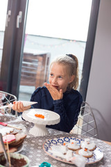 Wall Mural - Girl laughing while icing Christmas gingerbread cookies. Fun craft idea for all ages. Messy table.