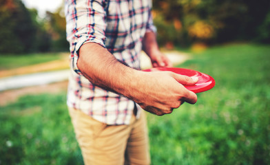 Man have fun with flying disc in the park, close up photo. Sport and recreation concept