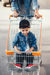 © teksomolika - Small boy, Mom carries in a cart near the supermarket.