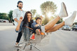 © teksomolika - Young dad carries mom and son in a cart on the parking lot