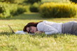 © oleg_chumakov - Business woman lying on a green grass and sleeping next to her laptop.