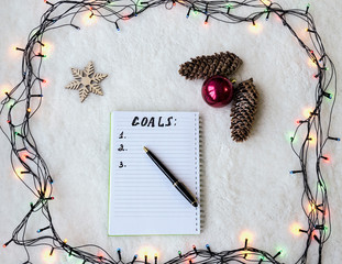 notebook with pen and phone on the background of Christmas garland