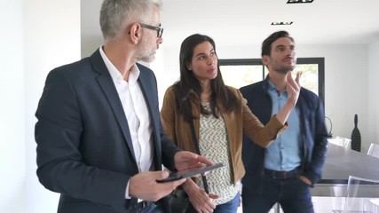 Wall Mural - Real estate agent showing modern house to potential buyer couple