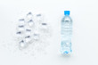 Frozen water in ice cubes and plastic bottle on white bar table top view mockup