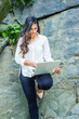 © Alexander Image - Young East Indian American Woman with long hair working on laptop computer outdoor in New York, wearing white shirt, black pants, high heels, standing by rocks at Central Park, looking down, reading..