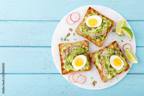 Cuadros en Lienzo Toasts with avocado guacamole, fresh radish, boiled egg, chia and pumpkin seeds