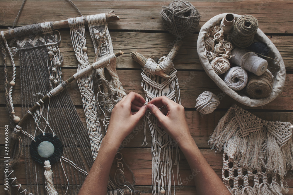 Female hands weaving macrame on a wooden table. Do it yourself. Top view. - obrazy, fototapety, plakaty 