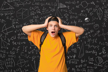 Shocked student standing by blackboard with math formulas