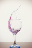 Fototapeta  - Splash of wine in a glass. Pink drink in glass on a white background.