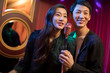 © Blue Jean Images - Happy young couple singing karaoke in nightclub