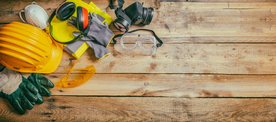 construction safety. protective hard hat, headphones, gloves and glasses on wooden background, banne