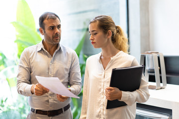 Wall Mural - Displeased executive showing to female manager data mistake in document. Male leader dissatisfied with work of young female employee. Problem concept