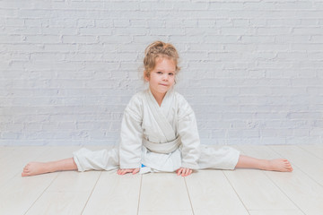 girl, a child in a kimono on karate training works out blows and greeting