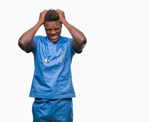 Poster - Young african american doctor man over isolated background wearing surgeon uniform suffering from headache desperate and stressed because pain and migraine. Hands on head.